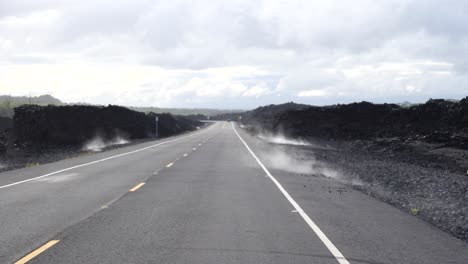 Low-angle-along-road-through-volcano-national-park-with-steam-rising-off-the-hot-magma-rock-into-the-road