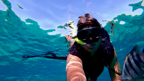 A-boy-snorkeling-and-swimming-on-water-surface-filming-video-selfie-with-snorkeling-mask-and-tube-|-Tourist-filming-his-snorkeling-experience