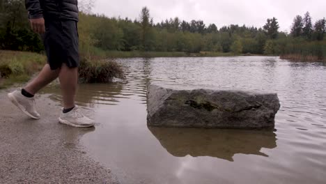 A-man-stepping-onto-a-big-rock-in-a-river