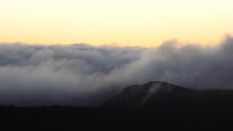 Thick-clouds-roll-off-mountains-during-sunrise