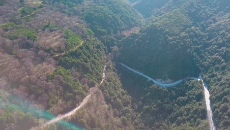 Forward-high-angle-aerial-shot-over-mountains-with-a-twisty-road