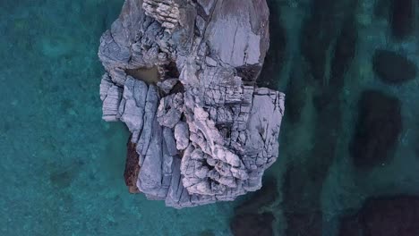 4K-Aerial-straight-down-still-drone-shot-of-a-big-rock-in-the-crystal-clear-waters-of-the-sea