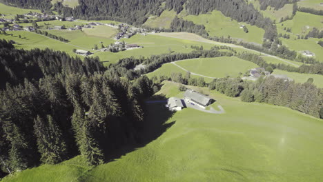 Aerial-drone-footage-flying-towards-grass-covered-hills-within-alpine-mountains-in-Tyrol,-Austria