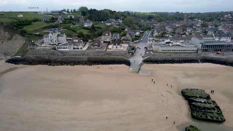 Aerial-panning-view-of-Arromanches-les-Bain,-Normandy-France-with-ww2-bunkers-on-beach