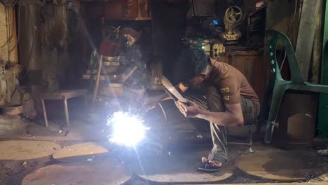 Teenage-welder-welding-at-a-factory-workshop-in-Dhaka,-Bangladesh
