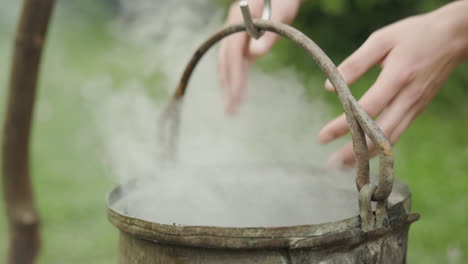 Witch-kettle-steaming-over-fire,-waving-hands-with-magical-spell,-slow-motion