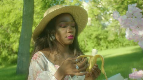 Black-Woman-eating-a-banana-in-park-circling-close-up