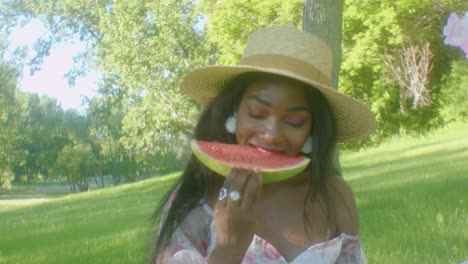 Slomo-frontal-of-black-lady-on-picnic-taking-bite-from-big-slice-of-watermelon