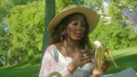 Mujer-Negra-Pelando-Tranquilamente-El-Plátano-En-Un-Picnic-En-El-Parque-De-Cerca