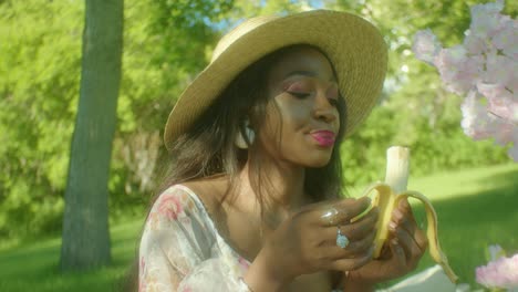 Black-Woman-eating-banana-chewing-in-park-dolly-in-close-up
