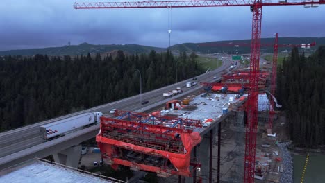 Crane-workers-on-bridge-construction-by-highway-bridge-tilt-and-pan