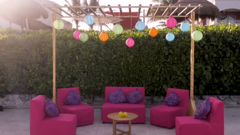 A-side-sliding-shot-of-a-pergola-decorated-with-lanterns,-couches-and-a-table