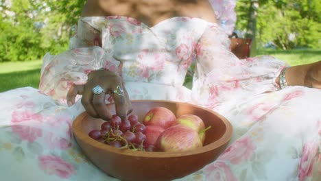 Black-Woman-picking-grape-and-apple-from-bowl-eating-on-a-picnic-in-park,-close-up