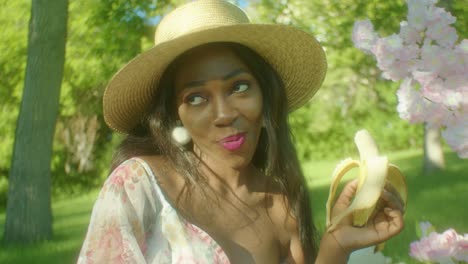 Mujer-Negra-Comiendo-Tranquilamente-Disfrutando-Del-Plátano-Sonriendo-En-El-Parque-Dolly-En-Primer-Plano