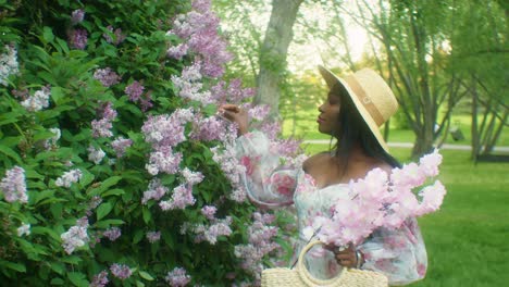 Black-Woman-playing-with-flowers-Lilacs-smiling-eye-contact-close-up
