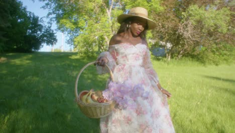 Black-Woman-walking-in-the-park-smiling-in-dress-with-basket-low-angle