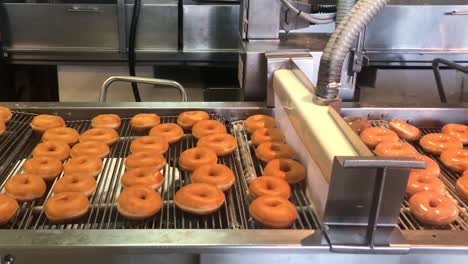Hunderte-Von-Frischen-Donuts,-Die-Von-Einer-Durchgehenden-Wand-Aus-Flüssigem-Zucker-Glasiert-Werden