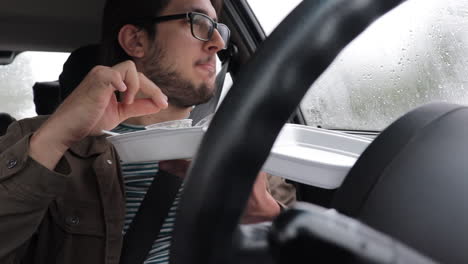 Slow-Motion-Man-Eating-Take-Away-In-His-Car-Alone,-Looking-Out,-Rainy-Day
