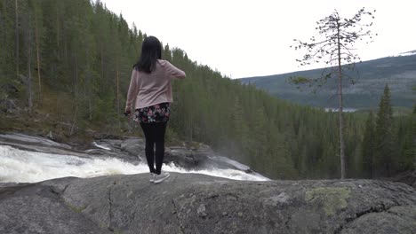 Girl-walks-by-a-waterfall