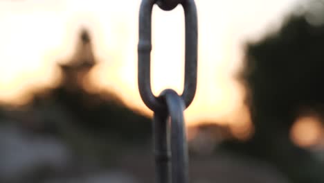 Eine-Starke-Eisenkette-Rückt-Vor-Dem-Hintergrund-Eines-Abnehmenden-Sonnenuntergangs-In-Den-Fokus