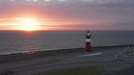 The-lighthouse-of-Westkapelle-during-a-bright-orange-sunset,-with-a-lot-of-wind