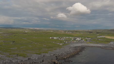 Drone-shot-showing-the-continent-and-grass-and-campground-near-the-Atlantic-Ocean-above-the-port-of-Doolin-by-the-Wild-Atlantic-Way-in-Doolin,-Co