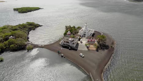 Drone-shot-of-Hindu-temple-surrounded-by-the-sea-in-Mauritius