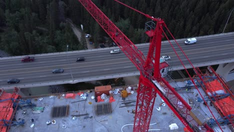 Crane-with-workers-by-busy-highway-bridge-construction-zone-above