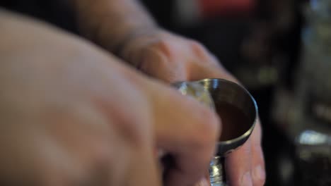 Pouring-liquor-into-measure-glass-to-prepare-cocktail-in-nightclub,-close-up