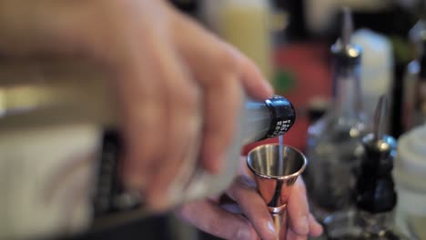 Bartender-pour-alcohol-to-metal-glass-preparing-cocktail,-close-up