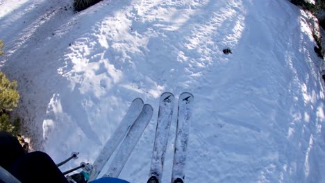 First-person-view-POV-of-two-people-riding-on-a-chair-lift-with-skis-covered-with-snow