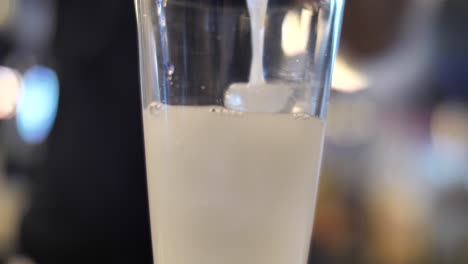 Alkoholischen-Cocktail-In-Glas-Mit-Eiswürfeln-Auf-Bartheke-Gießen,-Nahaufnahme