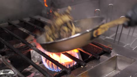 Professional-chef-mixing-and-frying-meat-and-mushroom-on-metal-pan,-close-up