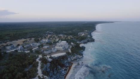 erial-dolly-drone-shot-of-the-coast-in-tulum-mexico-with-rocks,-sandy-beach-and-the-maya-ruins-with-view-to-the-cloudy-sky-4K