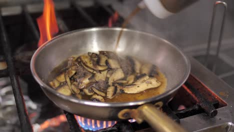 Adding-soy-sauce-to-champignon-mushroom-frying-on-pan,-close-up
