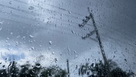 Closeup-of-rain-water-drops-dripping-on-window-surface-on-a-gloomy-cloudy-day