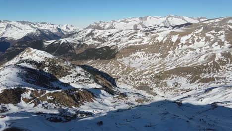Panoramic-view-flying-over-mountain-ridge-with-snowy-rocks