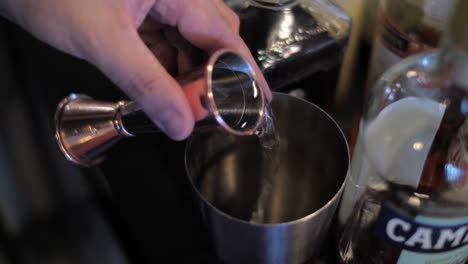 Bartender-pouring-liquor-into-shaker-preparing-cocktail,-close-up