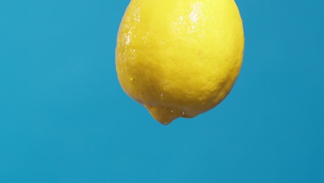 Wassertropfen,-Die-Aus-Einer-Ganzen-Sauren-Und-Frischen-Zitrone-Auf-Blauem-Hintergrund-Fließen,-Obst-Für-Frischen-Und-Natürlichen-Saft,-Kaltes-Diätgetränk-Mit-Vitamin-C