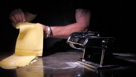 Chef-making-traditional-pasta-using-machine-to-cut-dough-in-kitchen,-close-up