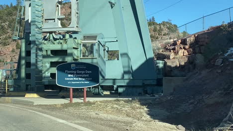 Flaming-Gorge-Dam-and-Poverplant-Sign-by-the-Road-Before-Passing,-Driver's-POV