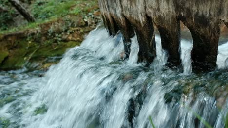 Close-up-of-gushing-water-through-wooden-sluice