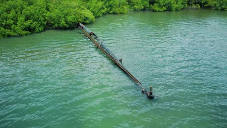 Close-up-aerial-shot-of-rusty-leaking-pipe-running-into-lake-surrounded-by-mangroves,-dumping-sewage