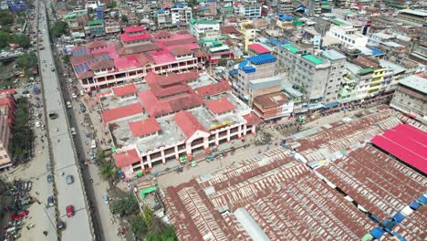 Aerial-Drone-Shot-Of-Ima-Market-Surrounded-By-Buildings,-Car,-People,-Bridges,-And-More-In-India