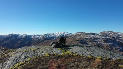 Landschaftsfotograf-Mit-Zoomobjektiv-Und-Stativ-Langsam-Umkreisen---Bergspitzenclip-Mit-Parallaxeneffekt-Im-Hintergrund-An-Einem-Schönen-Sonnigen-Herbsttag-In-Den-Bergen-Von-Nesheim-Eksingedalen-Norwegen