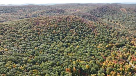 An-aerial-view-high-above-the-mountains-in-upstate-NY-during-the-fall-foliage-changes,-on-a-bright-and-sunny-day