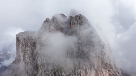 Mountain-peak-covered-in-clouds-by-Seceda-ridge-in-Italian-Dolomites,-aerial-view