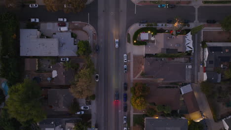 Drone-Shot-of-Cars-Driving-Slowly-Down-Street-As-Sun-Goes-Down,-Twilight-Traffic