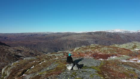 Flying-gently-over-young-male-landscape-photographer-sitting-on-mountain-peak-with-camera-and-tele-lens---Beautiful-sunny-autumn-day-in-norway-mountains-Eksingedalen