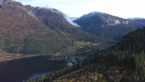Aerial-flying-over-hillside-to-Reveal-town-of-Kinsarvik-in-epic-surroundings-at-Ullensvang-Norway---Aerial-with-parallax-effect-during-sunny-autumn-morning